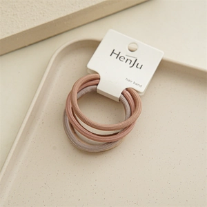 Detailed view of three elastic pink hair bands on a display card in a minimal tray