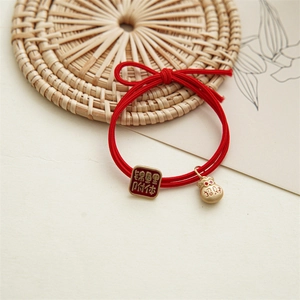 Détail d'élastique rouge avec breloque carpe koi en émail et pendentif sac de chance doré