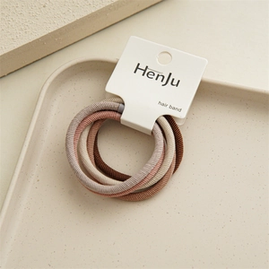 Macro view of four elastic hair bands with ribbed texture on a decorative beige tray
