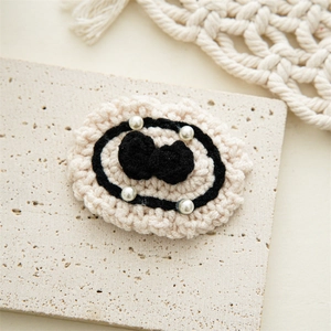 Detail view of handmade crochet hair clip with black bow and elegant pearls on white lace