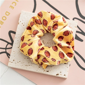 Detalle de un coletero de terciopelo amarillo con estampado de rugby sobre piedra beige