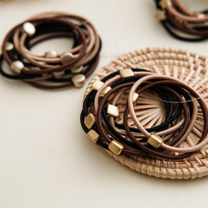 Detailed view of elastic hair ties in neutral tones on a textured woven mat background