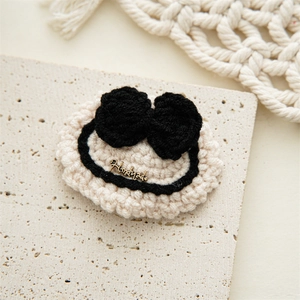 Detailed macro of handmade crochet hair clip featuring a bronze metal charm with text