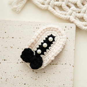 Macro shot of handmade crochet hair clip with a black bow and white pearls on stone