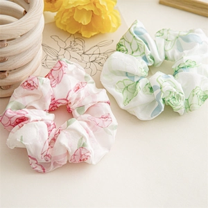 Close-up of vintage floral satin scrunchies with elegant rose patterns for hair styling