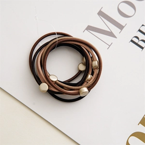 Detailed macro of coffee-toned elastic hair bands featuring matte gold metal buckles