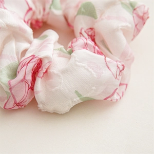 Close-up detail of pink floral satin scrunchie showing fine woven fabric texture