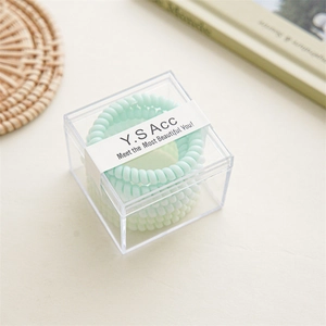 Detailansicht der minzgrünen Spiral-Haargummis in einer transparenten Acryl-Displaybox