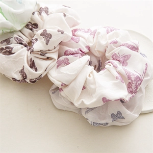 Close-up of floral satin scrunchies with butterfly patterns in brown, purple and green