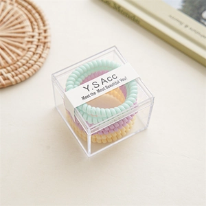 Macaron Spiral-Haargummis in einer transparenten Acrylbox auf einer Naturmatte