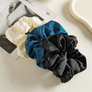 Three elegant satin silk hair scrunchies in cream white, peacock blue, and black colors