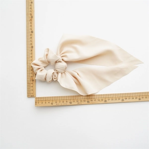 Elegant beige silk bow hair tie measuring 32cm long and 15cm wide on a white background