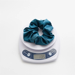 Detail showing high-quality dark cyan satin scrunchie weighing 13.5g on a scale