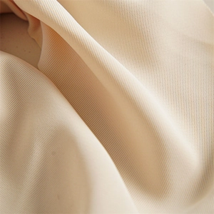 Detailed macro view of beige twill fabric hair scrunchie with soft draped texture