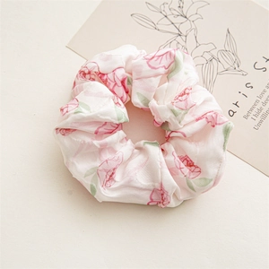 Close-up of a floral scrunchie with pink rose patterns on light chiffon fabric