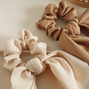 Close-up of beige and brown satin scrunchies with long ribbons on a tray