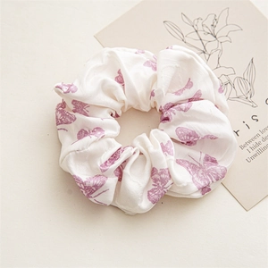 Detail of white satin scrunchie with purple butterfly floral prints and pleated fabric texture