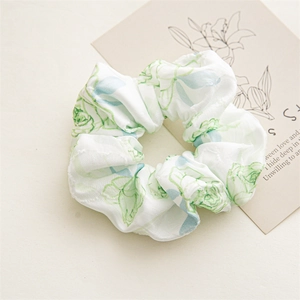 Close-up of floral satin scrunchie with green rose patterns and jacquard texture