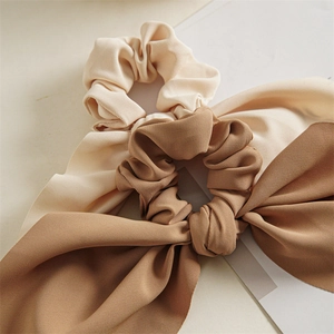 Close-up of cream and brown ribbon scrunchies showing elegant ribbed fabric texture