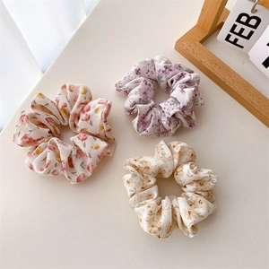 Vue détaillée de trois chouchous floraux en rose, violet et jaune avec texture en tissu doux