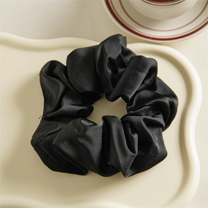 Detail of elegant black satin scrunchie on a stylish ceramic tray with a tea cup