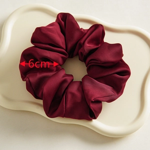 Detailansicht eines weinroten Satin-Haargummis mit 6cm Breite auf einem Wellentablett