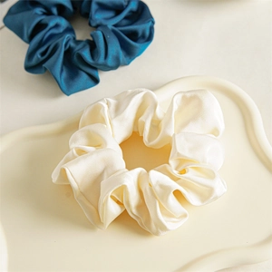 Detail showing creamy white and dark blue satin scrunchies with soft glossy texture