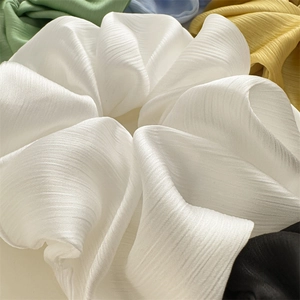 Vue macro de la texture plissée d'un grand chouchou blanc élégant et élastique pour cheveux