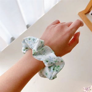 Détail d'un chouchou blanc à motifs floraux et marguerites porté au poignet délicat