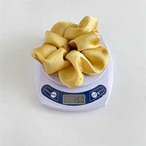 Chouchou élégant jaune vif de taille XXL pesant 15g sur une balance pour cheveux