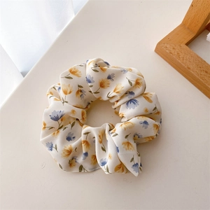 Vue détaillée du chouchou floral en polyester avec des fleurs jaunes et lilas sur fond beige