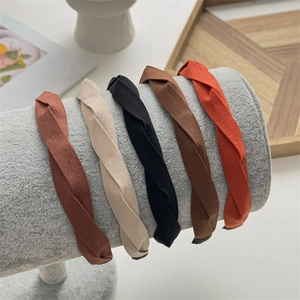 Detail showing five colors of twisted fabric headbands on a soft velvet display stand
