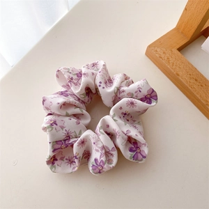 Gros plan du chouchou floral montrant la texture douce du tissu et les détails violets