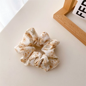 Vue détaillée d'un chouchou floral en tissu crème avec des motifs de fleurs colorées