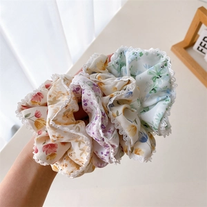 Détail de chouchous en tissu floral avec bordure en dentelle blanche et tons pastel