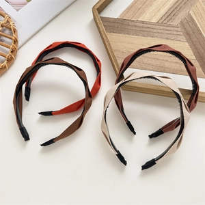Close-up of four pleated fabric headbands with anti-slip inner teeth in soft neutral colors