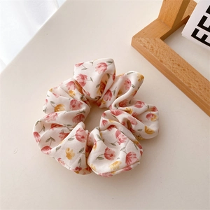 Détail d'un chouchou en tissu crème avec des motifs floraux roses et jaunes doux