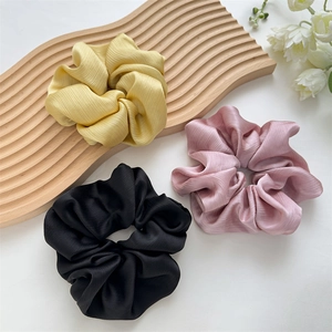 Vue détaillée de grands chouchous plissés en jaune, rose et noir en tissu de soie