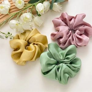 Détail de trois chouchous plissés rose, jaune et vert avec des textures verticales douces
