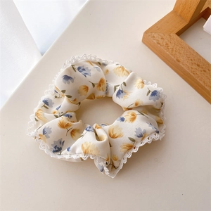 Chouchou fleuri avec bordure en dentelle blanche et fleurs bleues dans un décor clair