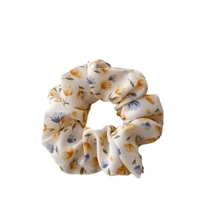 Chouchou floral en mousseline avec motifs bleus et jaunes sur tissu blanc cassé