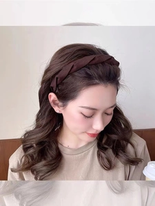 Detailed view of model wearing a dark brown twisted fabric headband in a soft indoor light