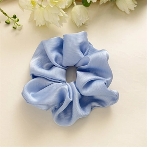 Gros plan sur un chouchou élégant bleu clair en satin avec des plis texturés doux