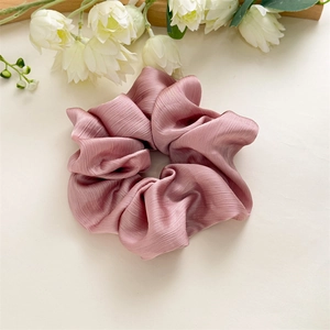 Gros plan d'un chouchou géant rose poudré plissé avec une texture soyeuse et brillante