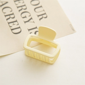 Détail macro d'une pince à cheveux rectangulaire jaune crème mat au design ajouré