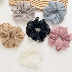 Mise à plat de 6 chouchous géants en organza transparent aux tons pastels sur fond naturel
