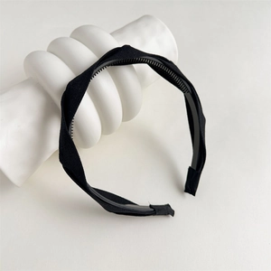 Close-up of black fabric twisted headband with non-slip teeth on a white display