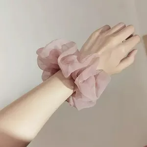 Détail d'un chouchou géant en organza rose avec des plis doux portés sur le poignet