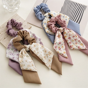 Detail view of floral fabric bow hair scrunchies in purple, brown, blue, and pink colors