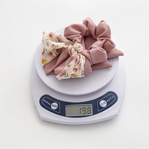Floral print bow hair scrunchie in lotus pink weighing 19.8g on a digital scale